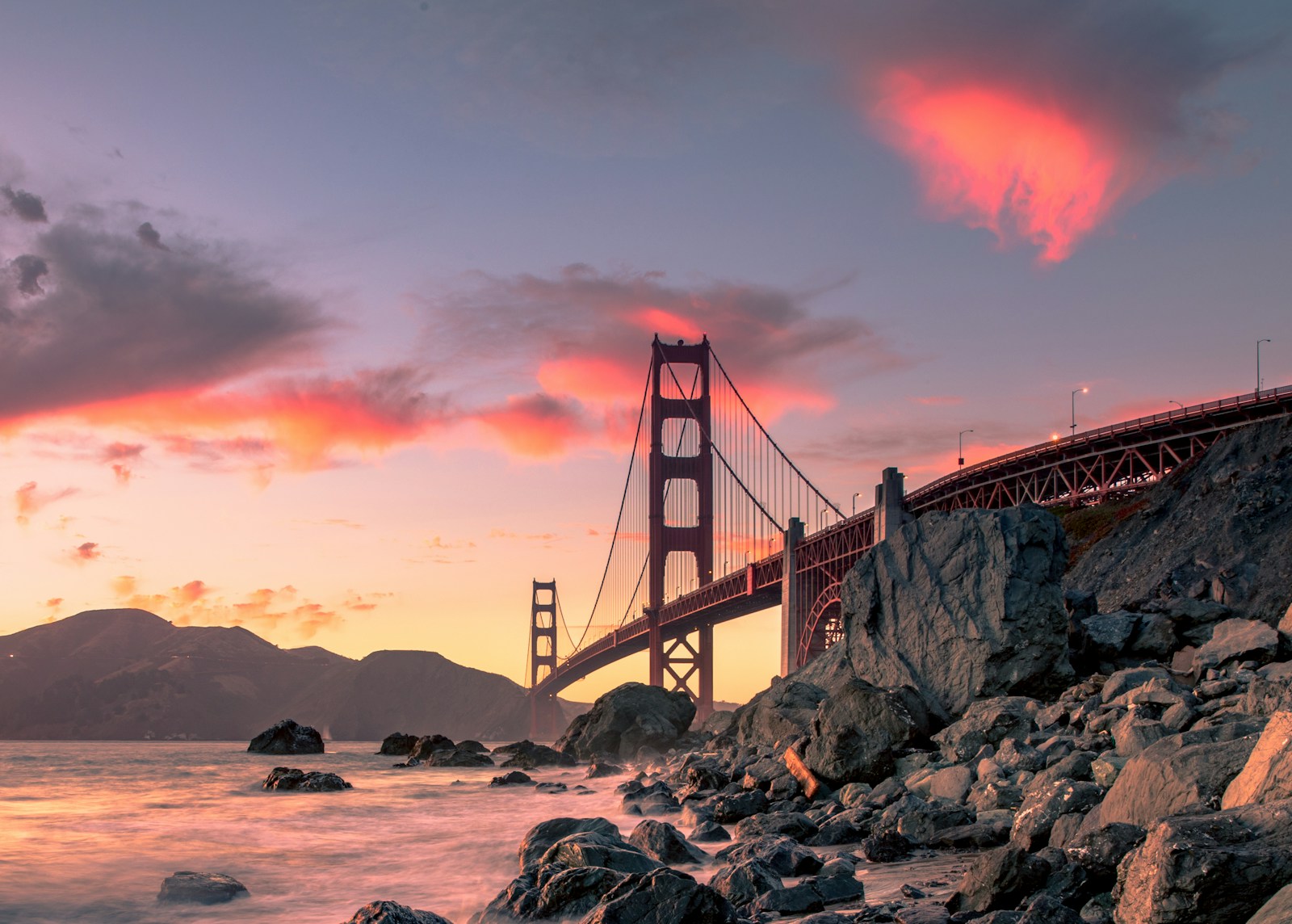 The Golden Gate Bridge from the rocky shoreline at sunset